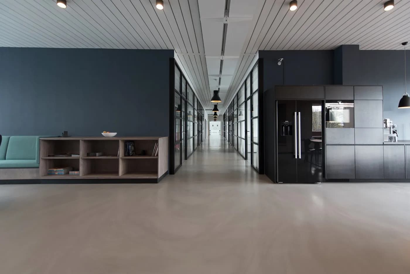 A modern open-plan office corridor with meeting rooms